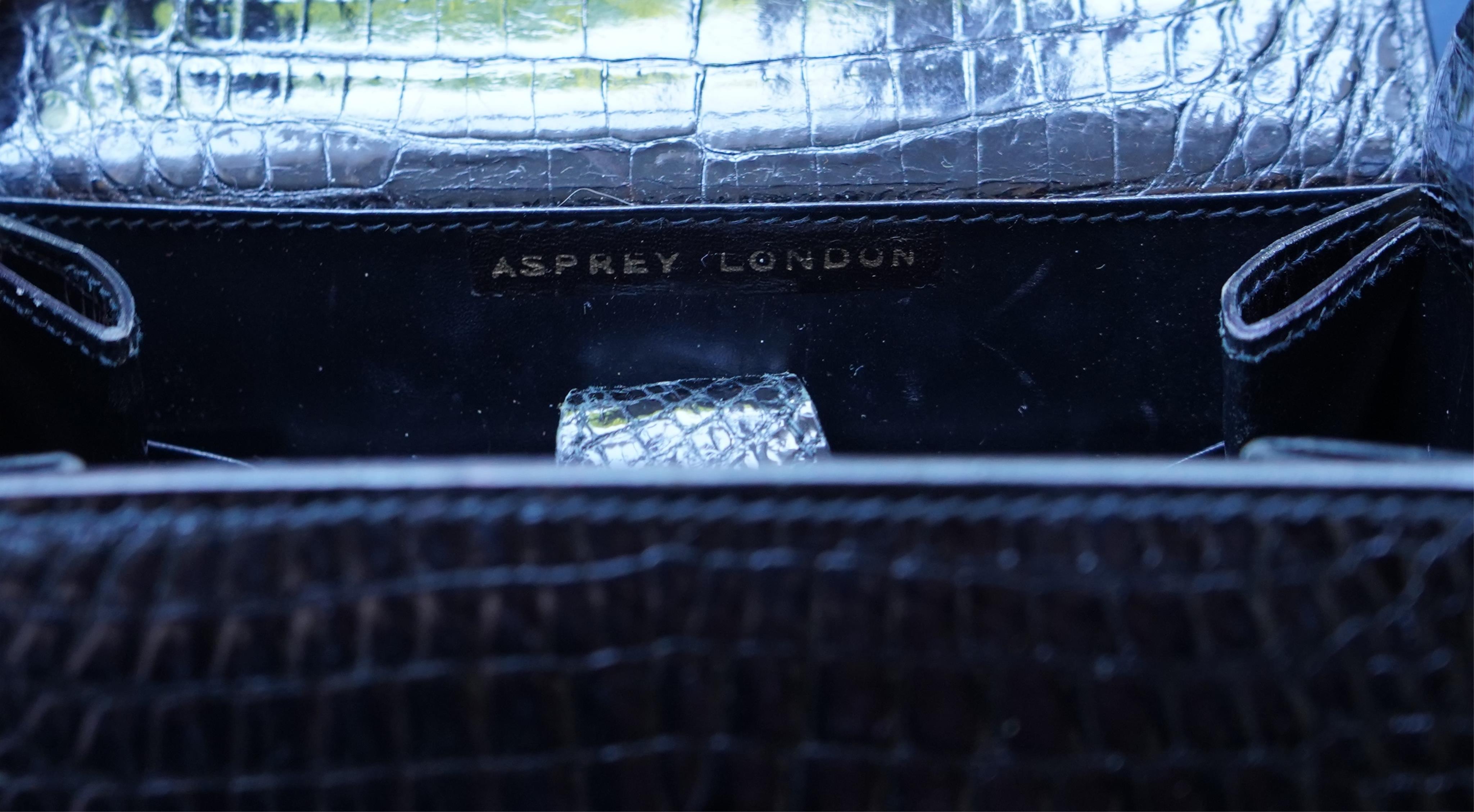 A stylish 1930’s lady’s Asprey of London, black lizard skin evening bag with ornamental amber coloured Bakelite clasp. 23cm high from handle to base. Condition- some internal scratches to lining as expected for age and u
